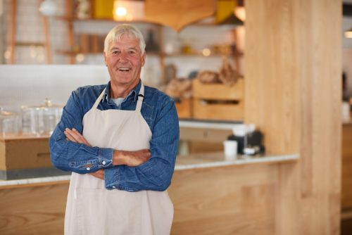 Portrait of a confident senior business owner posing with an apron on in his coffee shop